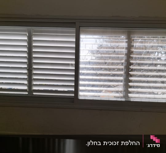 תריסים לבנים סגורים על חלון זכוכית